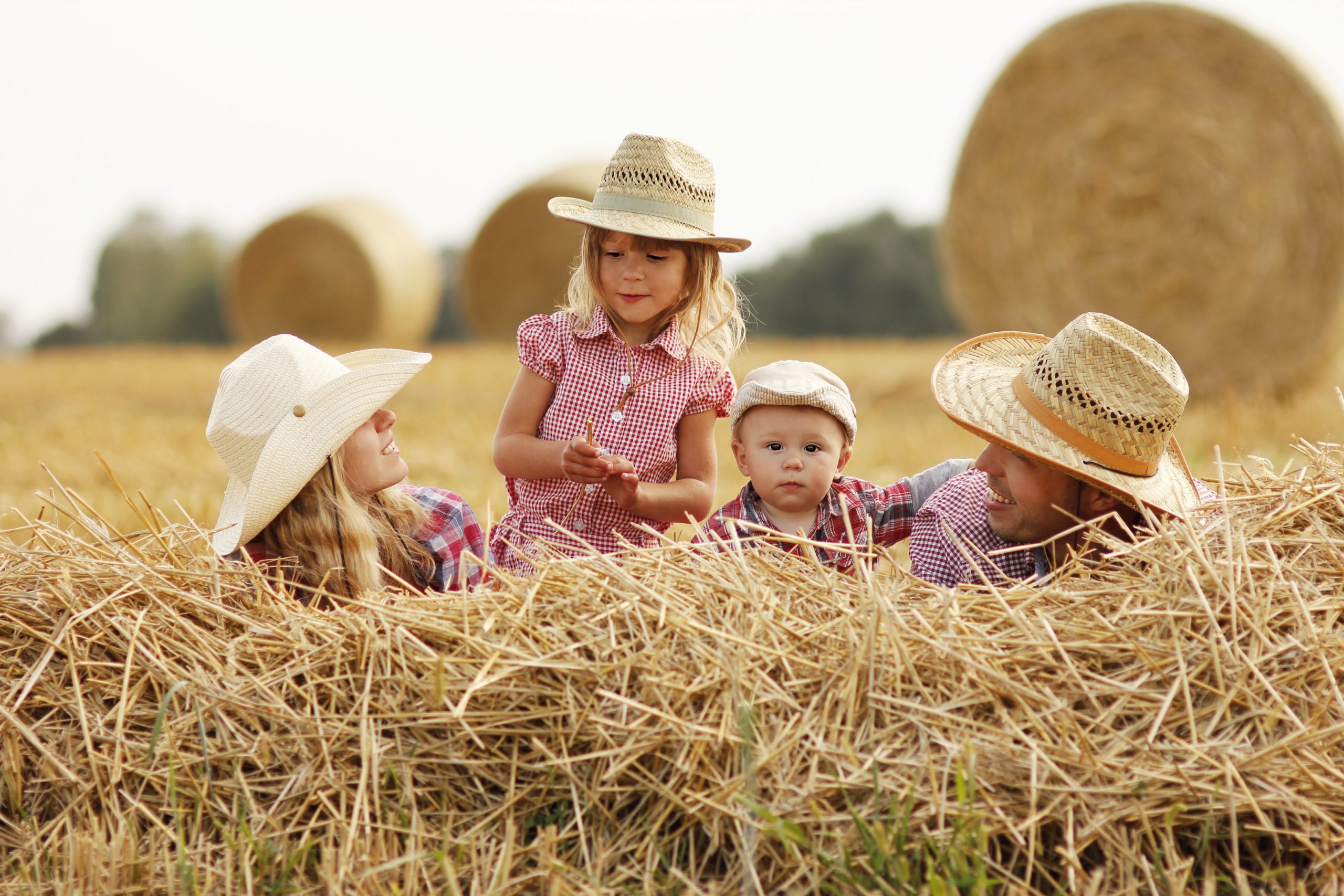 Familie auf Heuhaufen mit Cowboyhüten