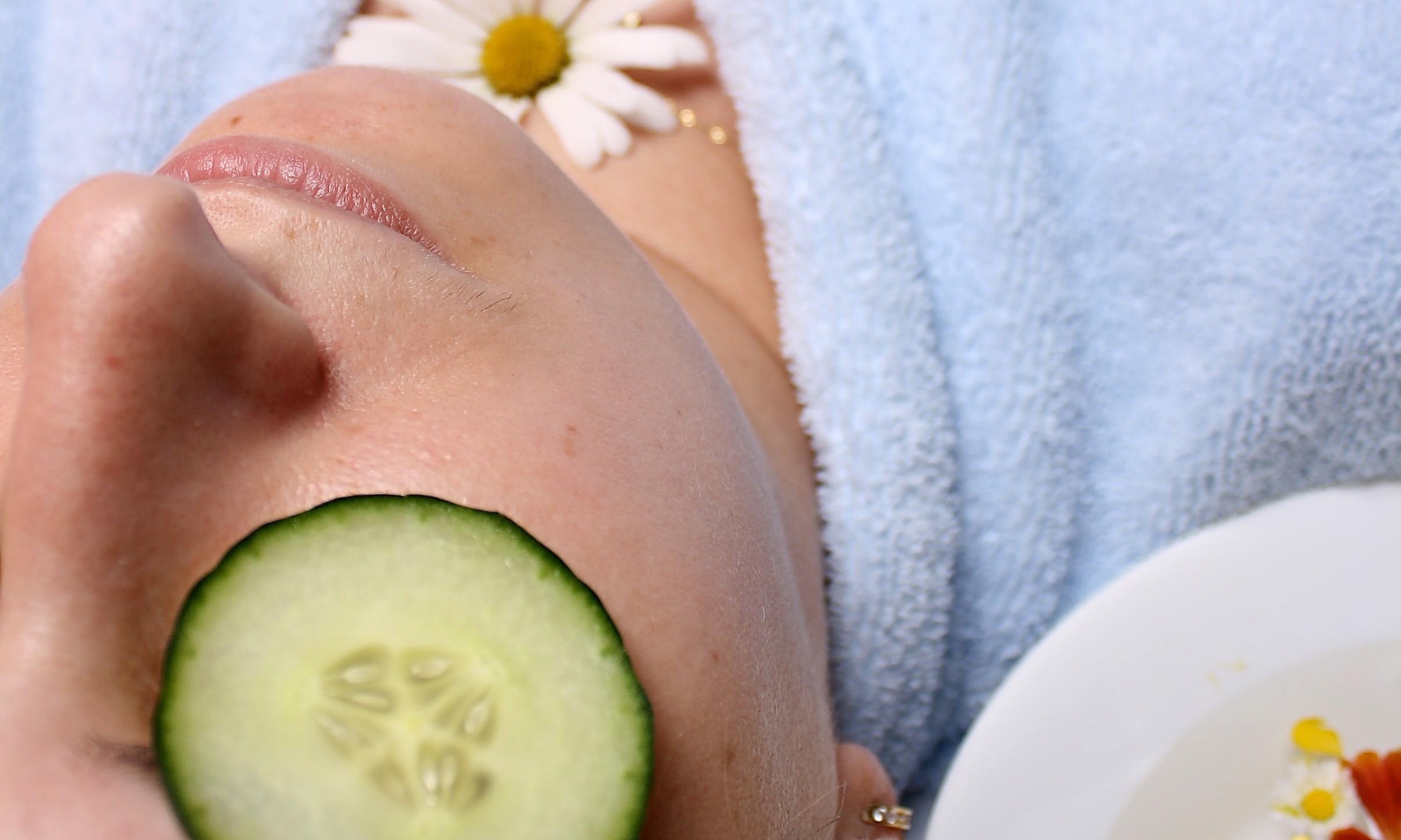 Beauty Behandlung. Frau mit Gurkenscheibe auf dem Auge und Margarete am Hals