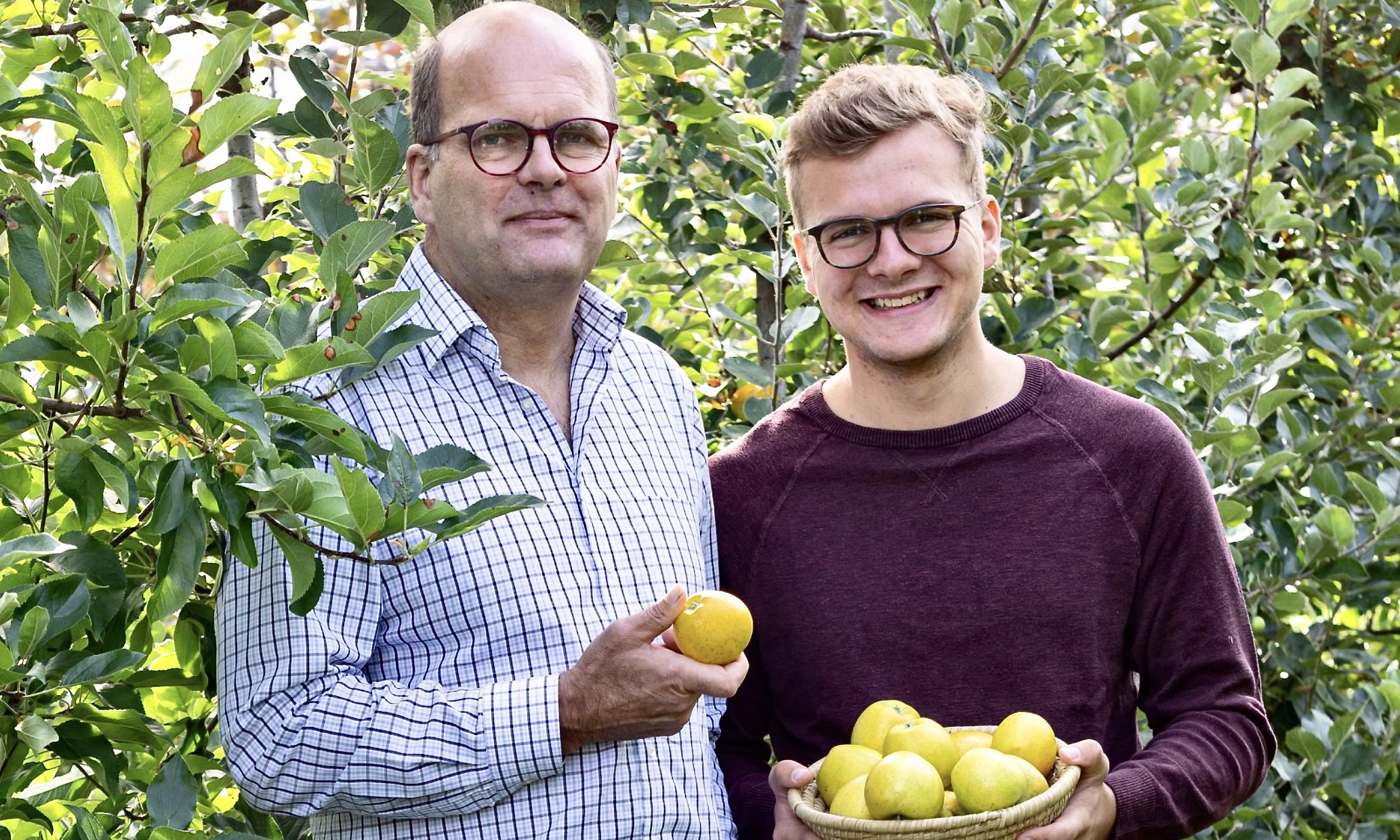 Mann mit Apfel in der Hand, junger Mann mit Apfelkorb